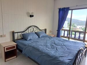 a bedroom with a bed with blue sheets and a window at Bo House in Patong Beach