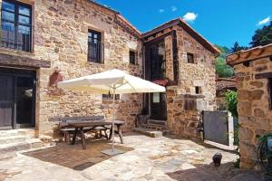 un edificio in pietra con tavolo e ombrellone di Casa Rural con encanto en plena Reserva de Urbión. a Vinuesa