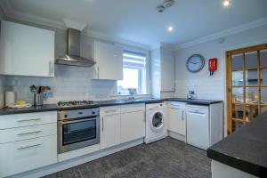 a kitchen with white cabinets and a washer and dryer at The Brigg in Coatbridge