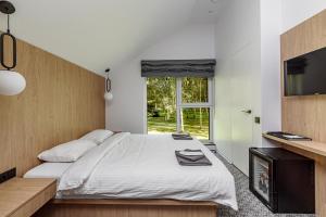 Schlafzimmer mit einem Bett, einem TV und einem Fenster in der Unterkunft Molėtairesort in Molėtai
