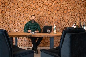 un uomo seduto su un tavolo di legno con un portatile di Altitude Lodge Hotel a Campos do Jordão