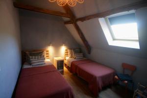een slaapkamer op zolder met 2 bedden en een raam bij Gite Bellevue in Saint-Pierre-Toirac