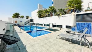 a swimming pool with two chairs next to a building at Tanin - Affordable Luxury and Fully Furnished 1BR in JVC in Dubai