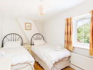 two beds in a room with a window at Pass the Keys Conventional and Homely 3Bed in Alderminster in Stratford-upon-Avon