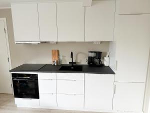 a kitchen with white cabinets and a black counter top at Tromsdalen Aurora Apartments in Tromsø