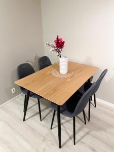 drewniany stół z czarnymi krzesłami i wazon z kwiatami w obiekcie Tromsdalen Aurora Apartments w mieście Tromsø