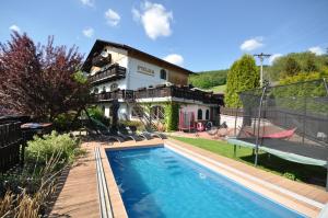 a house with a swimming pool in front of a house at Wellness Pension Fulda Černý Důl in Černý Dŭl