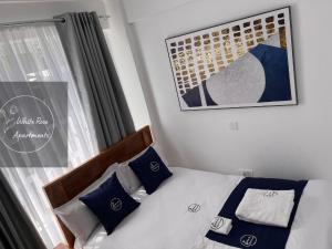 Schlafzimmer mit einem Bett mit blauen und weißen Kissen in der Unterkunft WhiteRose Apartments in Meru