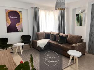 sala de estar con sofá marrón y 2 mesas en WhiteRose Apartments, en Meru