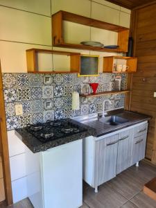 a kitchen with a stove and a counter top at Essência da Terra - Cabanas de Temporada in Praia do Rosa