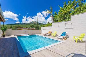 einen Pool im Hinterhof mit Stühlen und einem Tisch in der Unterkunft Heliconia - Appt avec piscine partagée in Saint-Pierre