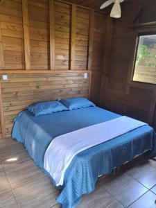 a large bed in a room with wooden walls at Essência da Terra - Cabanas de Temporada in Praia do Rosa