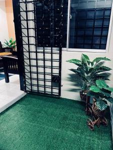 Habitación con alfombra verde y puerta con plantas. en Daliya Homestay Ulu Tiram JB, en Ulu Tiram