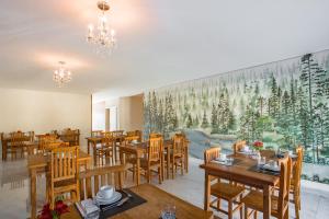 um restaurante com mesas e cadeiras de madeira e uma grande pintura em Altitude Lodge Hotel em Campos do Jordão