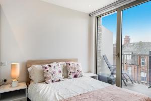 a bedroom with a bed and a large window at Utopian Apartments Kilburn in London