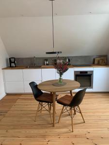 una cocina con una mesa con sillas y un jarrón de flores en Ostseeloft, en Flensburg