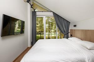 een slaapkamer met een groot bed en een raam bij Miško Spa namas in Molėtai