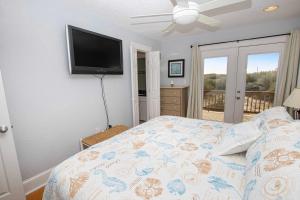 a bedroom with a bed with a tv on the wall at Oceanside, Hot Tub, Screened Porch, Wild Horses, 4x504, Sol Searcher in Corolla