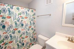 a bathroom with a shower curtain with a toilet and a sink at Oceanside, Hot Tub, Screened Porch, Wild Horses, 4x504, Sol Searcher in Corolla +25 photos
