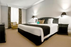 een hotelkamer met een groot bed en een stoel bij Dann Carlton Quito in Quito