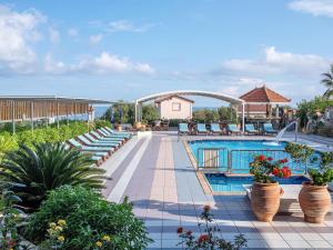 a swimming pool with chairs and plants in a resort at Evalia Apartments in Hersonissos