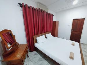 a bedroom with a bed and a mirror and red curtain at HOSTEL KATUNAYAKE At COLOMBO AIRPORT TRANSIT in Katunayaka