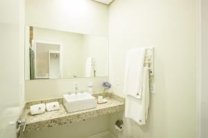 a white bathroom with a sink and a mirror at Altitude Lodge Hotel in Campos do Jordão +20 photos