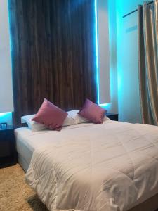 uma cama branca com almofadas cor-de-rosa num quarto em Sunset Views Sharifia Villa em Marrakech