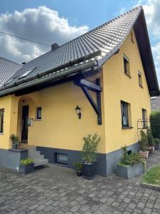 a yellow house with a solarium on the side of it at Ferienwohnung Klatschmohn in Wallscheid