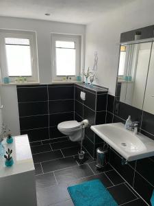 a bathroom with a white toilet and a sink at Ferienwohnung Klatschmohn in Wallscheid +4 photos
