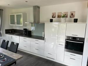 a kitchen with white cabinets and a black counter top at Ferienwohnung Klatschmohn in Wallscheid