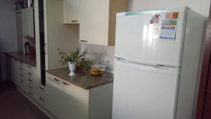 einen weißen Kühlschrank in einer Küche mit einer Theke in der Unterkunft RESIDENCIAL BOTÂNICO in Curitiba