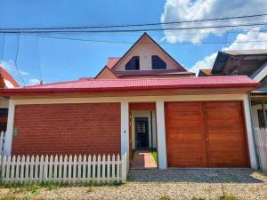 a red brick house with a white fence at Casa Belgrado, te espera. in Oxapampa