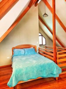 a bedroom with a bed with blue sheets in a attic at Casa Belgrado, te espera. in Oxapampa