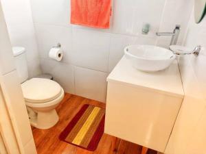 a white bathroom with a toilet and a sink at Casa Belgrado, te espera. in Oxapampa