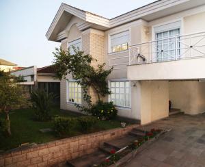 a white house with a balcony and a yard at RESIDENCIAL BOTÂNICO in Curitiba