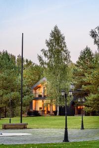 ein Haus mit zwei Lichtern und einer Bank in einem Park in der Unterkunft Pirties Spa namas in Molėtai