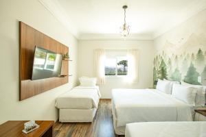 a bedroom with two beds and a tv and a couch at Altitude Lodge Hotel in Campos do Jordão +22 photos