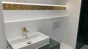 lavabo blanco en el baño con aaucet en Luxliv Apartements, en Balingen