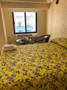 Un dormitorio con una cama con un edredón colorido y una ventana en Eurohotel en Ciudad del Carmen