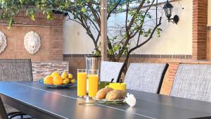 una mesa negra con fruta y zumo de naranja. en VILLA ROSARIO entre Granada y Sierra Nevada, en La Zubia