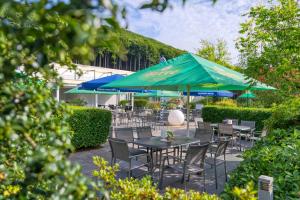 un patio con tavoli, sedie e ombrelloni di Hotel Wiehen-Therme a Hüllhorst