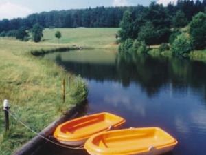 deux bateaux sont attachés au bord d'une rivière dans l'établissement Ferienhauser Siefertshof, à Mossautal