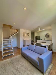 a living room with a blue couch and a staircase at Flats Chateau Campos do Jordão in Campos do Jordão