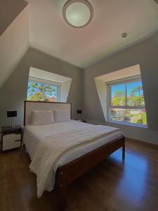 a bedroom with a large bed and two windows at Flats Chateau Campos do Jordão in Campos do Jordão