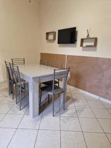 een eettafel met stoelen en een flatscreen-tv bij La Domus Pompei Casa vacanza in Pompei