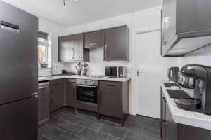 a kitchen with stainless steel appliances and brown cabinets at Lavender Lodge - Near Shops & with Free Parking in Haywards Heath
