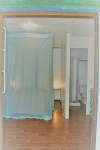 a room with a bed with a blue curtain at Bungalow Caraïbes, proche de la route mais calme la nuit. in Trois-Rivières