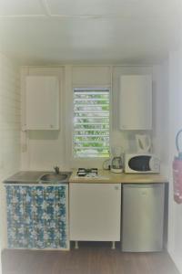 a small kitchen with a sink and a window at Bungalow Caraïbes, proche de la route mais calme la nuit. in Trois-Rivières