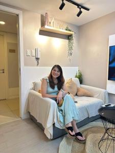 a woman sitting on a bed in a room at AZURE URBAN RESORT RESIDENCE R&C - Parañaque in Manila